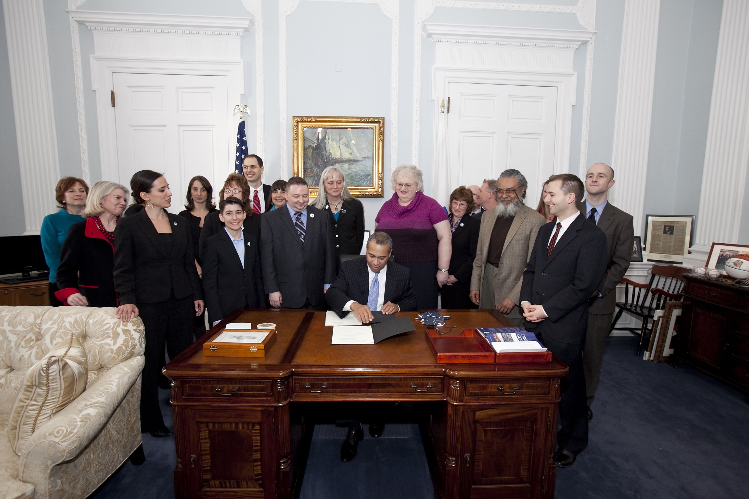 Gov Deval Patrick signs Executive Order surrounded by crowd of supporters, including MassEquality staff.